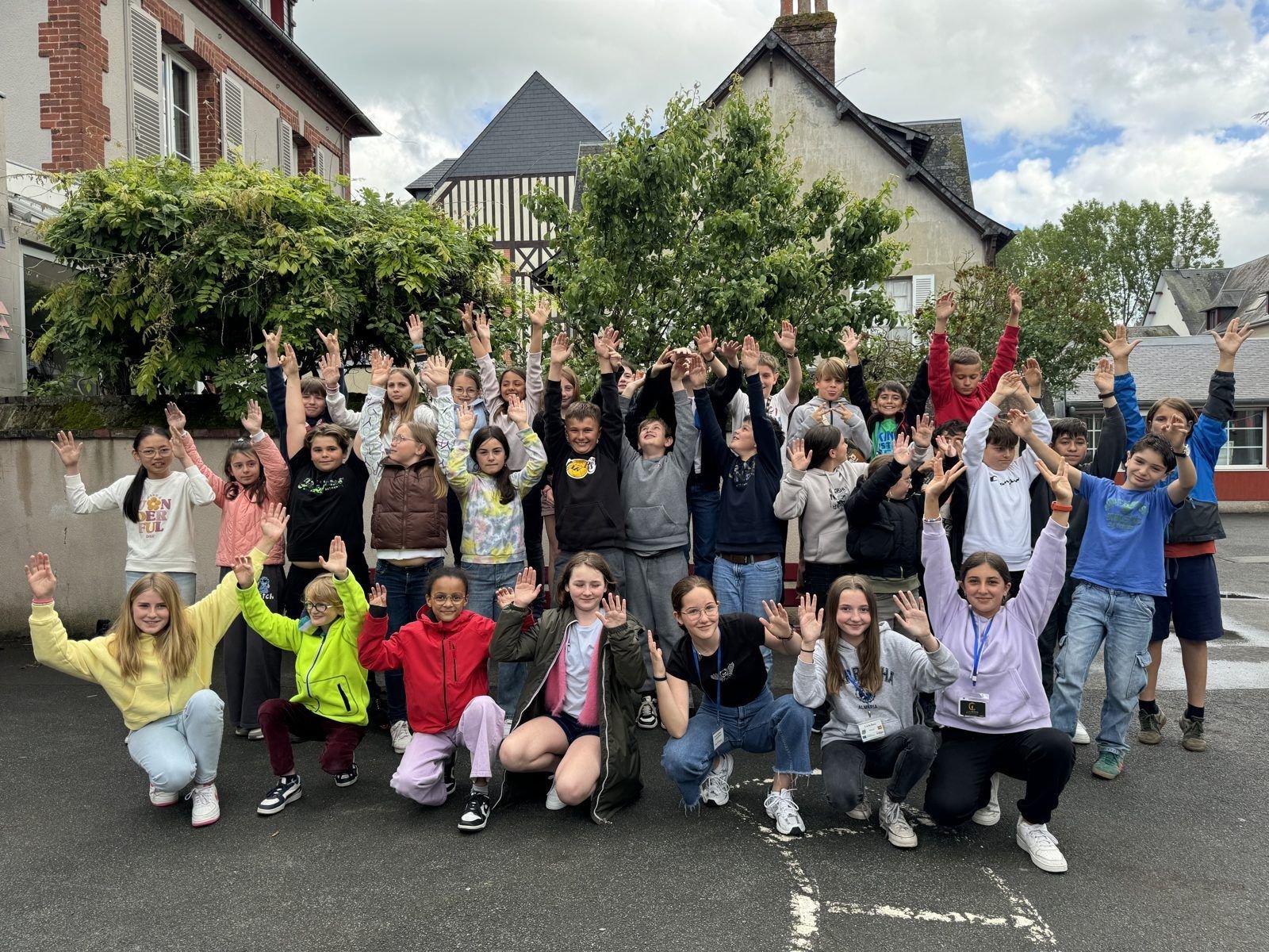 Alumnes de l'escola i de l'escola sòcia saludant amb els braços enlaire en una mobilitat a Normandia